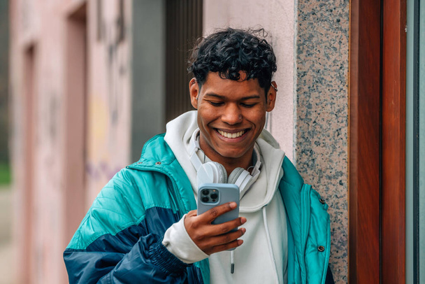 jeune latino homme dans la rue avec téléphone portable ou cellulaire - Photo, image