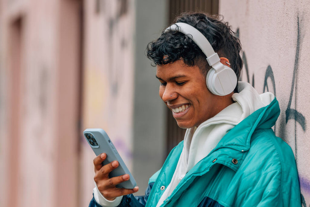 joven latino urbano con teléfono móvil y auriculares en la calle - Foto, imagen