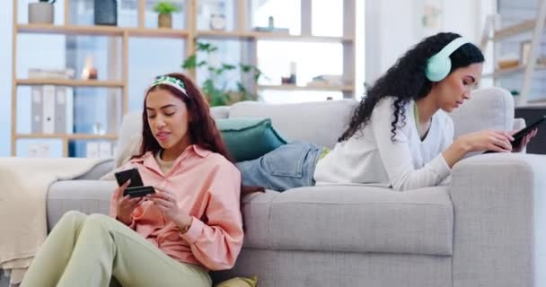 Technology, relax and a gay couple in the living room of their home together for music or online shopping. Tablet, phone and credit card with an lgbt woman and girlfriend on a sofa for ecommerce. - Footage, Video