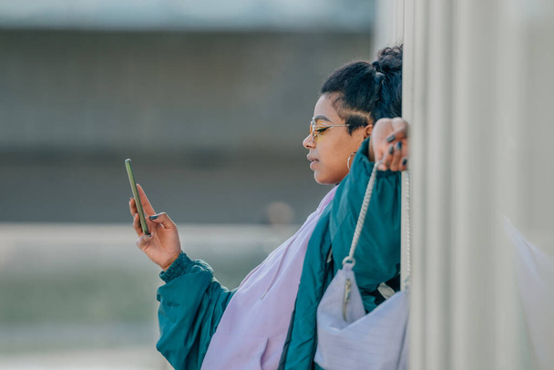 девушка на улице с мобильным телефоном на стене с копировальным пространством - Фото, изображение