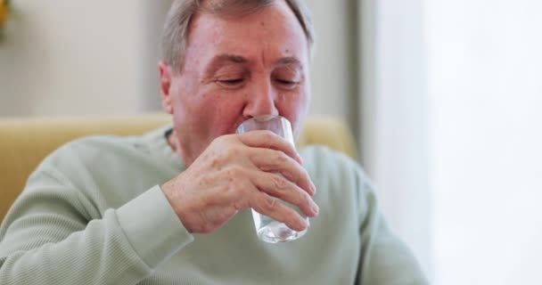 Πόσιμο νερό, ηλικιωμένος και Πάρκινσον ή τρέμουλο με τρεμάμενα χέρια σε έναν καναπέ στο σπίτι. Άρρωστος ηλικιωμένος με αναπηρία, γυαλί και νευρολογία, μύες ή ανακινητική ασθένεια κατά τη συνταξιοδότηση. - Πλάνα, βίντεο
