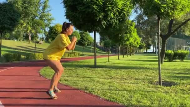 Активна багаторасова молода жінка бере участь у відродженні ранкових фізичних вправ у золотому сонячному світлі нового дня. Вона прогрівається, роблячи бадьоре тренування в громадському парку вдень. 360 градусів постріл - Кадри, відео