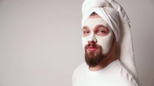 Uomo in camicia bianca applicare maschera facciale stand contro sfondo bianco. Trattamento estetico, cura e concetto di benessere. Self care mattina procedura spa - Filmati, video