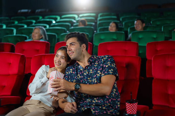 A párok élvezik a filmeket, miközben popcornt tartanak, hangulatos és szórakoztató moziestet teremtve a moziban.. - Fotó, kép