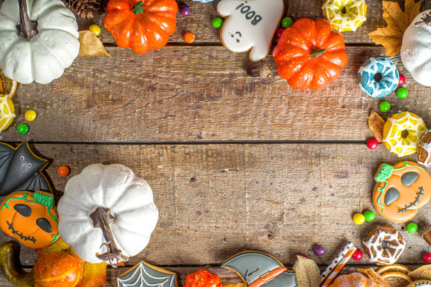 Halloween-Plätzchen, Süßigkeiten und Deko-Hintergrund. Trick- oder Behandlungskonzept. Traditionelle Halloween-Lebkuchen, Bonbons mit Kürbissen und Dekorationen auf hölzernem Hintergrund - Foto, Bild
