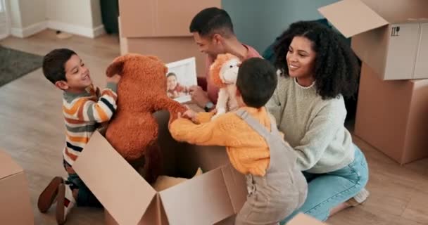 Przenoszenie się, zabawki i rodzice z dziećmi z kartonowymi pudełkami w nowym domu łączącym się ze sobą. Szczęśliwi, uśmiechnięci i młodzi ludzie bawiący się pluszowymi misiami ze swoimi chłopcami w nowoczesnym domu - Materiał filmowy, wideo