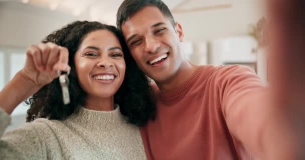 Selfie of happy couple in living room with keys to new home, investment and mortgage for property. Real estate, man and woman with smile, marriage and safety, celebration in dream house for future - Footage, Video