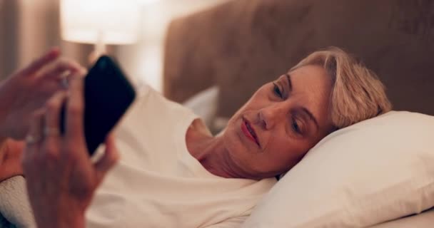 Nacht, App und eine Frau mit einem Handy im Bett für soziale Medien, Chat oder Internet. Haus, Website und eine ältere Person tippen auf einem Handy für Kontakt, Kommunikation oder Benachrichtigung im Schlafzimmer. - Filmmaterial, Video