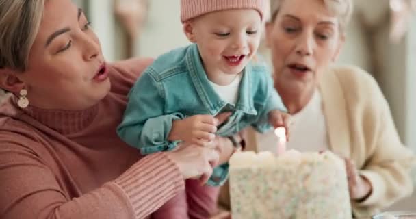 Birthday cake, blowing candle and child with family to celebrate development with dessert. Party, surprise or social gathering with mother, happy kid and grandmother clapping at table for fun at home. - Footage, Video