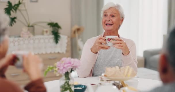 Чай, смешная и пожилая женщина с друзьями в домашней гостиной, связи и говорить за столом. Счастливые люди, пожилые люди и смеющиеся над комедией, историей и улыбкой для разговора, глотка и кофе. - Кадры, видео
