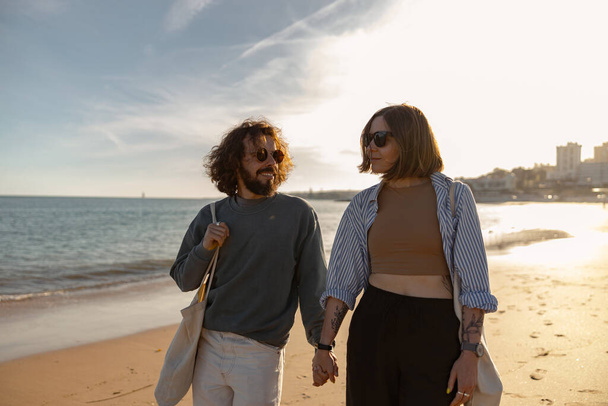 Boldog romantikus szerelmesek sétálnak kéz a kézben a napos tengerparton. Kiváló minőségű fénykép - Fotó, kép