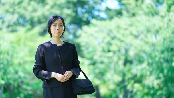 Una donna in lutto vestiti in piedi in uno spazio verde - Foto, immagini