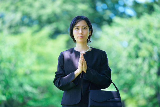 A woman who puts her hands together in a mourning dress outdoors - Photo, Image