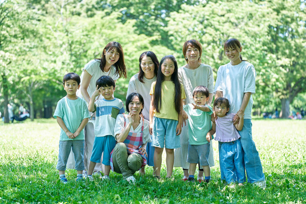 Grupowe zdjęcie dzieci, rodziców i nauczycielki w parku - Zdjęcie, obraz