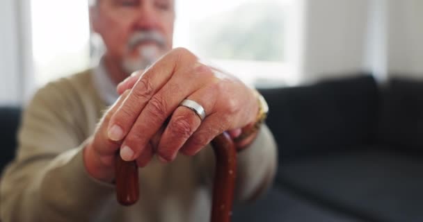 Bastón, apoyo y pensamiento con las manos del anciano en el sofá para la jubilación, médico y relajarse. Cuidado de la salud, artritis y bastón para caminar con el primer plano de la persona mayor en el hogar de ancianos para la osteoporosis. - Metraje, vídeo