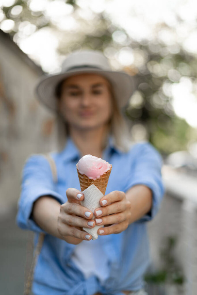 Καλοκαιρινό επιδόρπιο και χαρούμενη καλοκαιρινή διάθεση. Υγιή vegan παγωτό φράουλα γρανίτα στο χέρι της νεαρής γυναίκας στο παρασκήνιο. Επιλεκτική εστίαση - Φωτογραφία, εικόνα