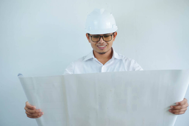 giovane asiatico maschio architetto ingegnere sorridente e Holding ingegneria cianografie isolato su sfondo bianco. - Foto, immagini