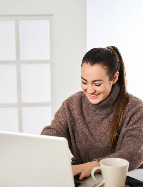 a smiling woman working energetically on her personal computer from her office at work - Photo, Image