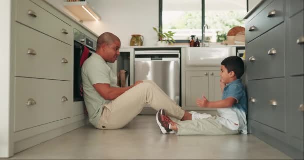 Father, son and games on the kitchen floor with a family in their home together friendly competition. Kids, love and a man playing with his young child while having fun or laughing while bonding. - Video