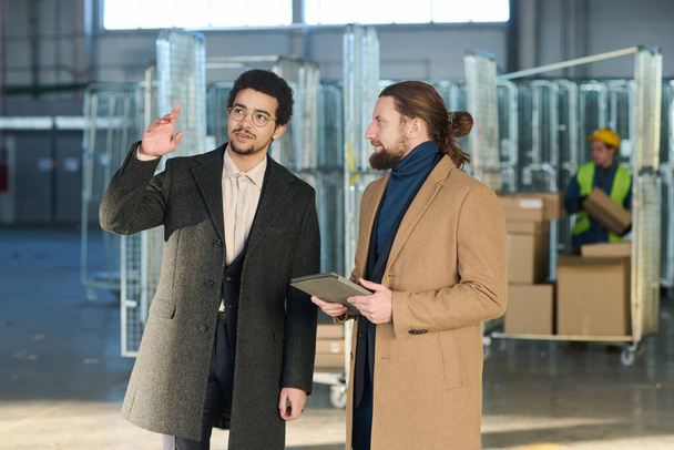 Двоє молодих міжкультурних бізнесменів або підприємців у формальному одязі обговорюють площу свого офісу, стоячи в незавершеному будинку - Фото, зображення