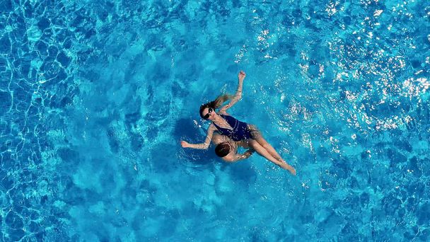 Vista dall'alto. La coppia si diverte in piscina. Una giovane coppia attraente è rilassante in piscina. Godersi la compagnia a vicenda. - Foto, immagini