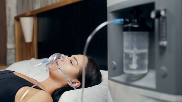 Ritratto di una giovane donna malata che utilizza un concentratore di ossigeno e un inalatore per il trattamento a casa. Covid-19, asma bronchiale. Trattamento, trattamento e procedure, terapia. - Foto, immagini