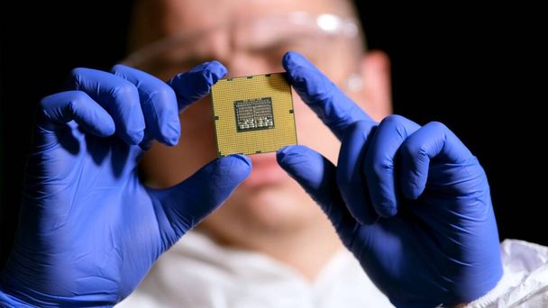 Ingénieur homme en costume stérile tient Microchip avec des symboles dans l'usine de conception moderne, concept d'intelligence futuriste et artificielle - Photo, image