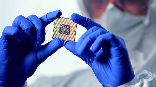 Ingenieur man in steriel pak houdt Microchip met symbolen in moderne design fabriek, futuristische en kunstmatige intelligentie concept - Foto, afbeelding