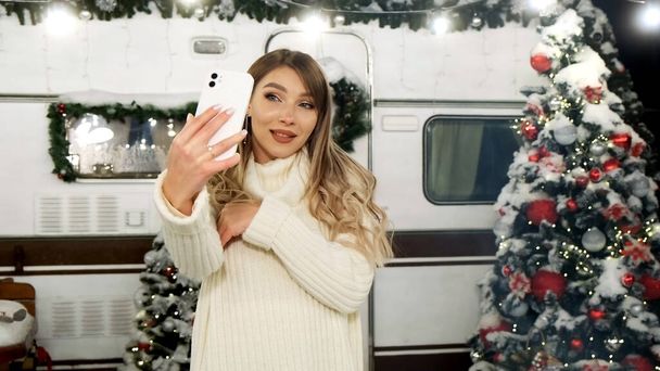 Nő nevet pózol, és szelfit készít karácsonyfa háttér szabadban. Blogger videózik. Téli nyaralás koncepciója. - Fotó, kép