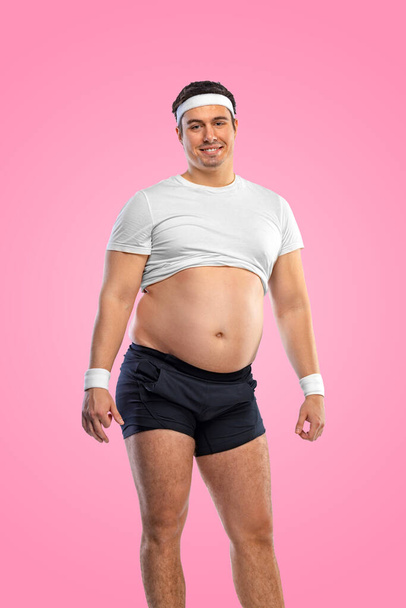 非常に太った男はクリームで自分自身をジョージします. 肥満と摂食障害について。 ソーシャルネットワークにおける栄養士とフィットネス広告のコンセプト - 写真・画像