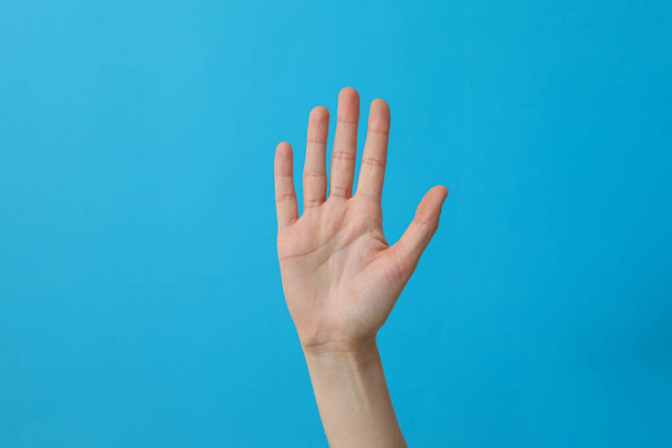 Mano femminile mostrando cinque dita su uno sfondo blu - Foto, immagini