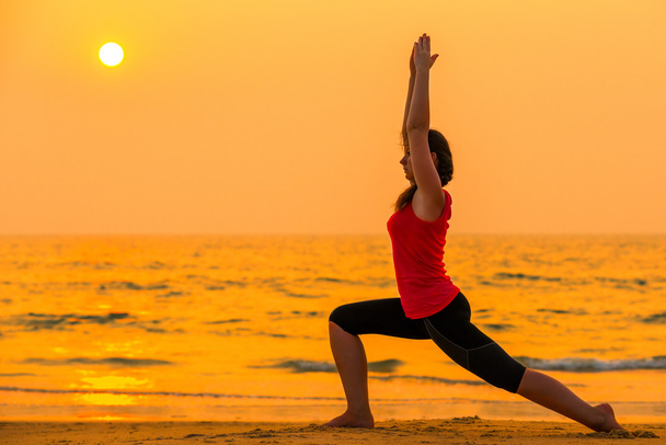 nainen harjoittaa joogaa auringonlaskun lähellä merta
 - Valokuva, kuva