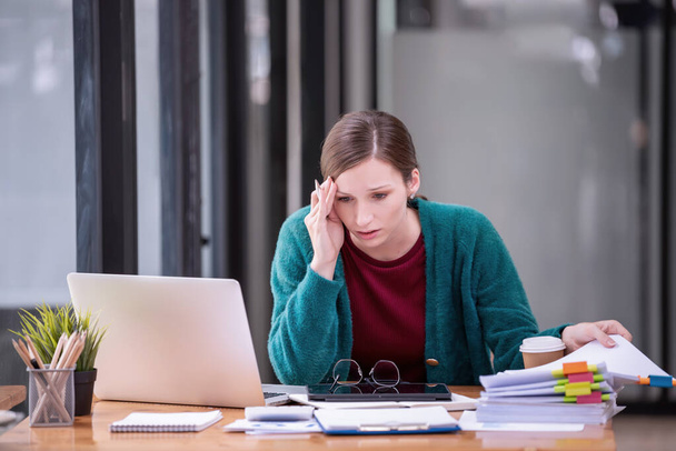 Zakelijke vrouwen zijn gestresst met werk voor een laptop en papieren documenten in het kantoor. Bedrijfsconcept. - Foto, afbeelding