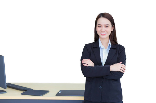 Mulher trabalhadora profissional asiática que tem cabelo longo usa terno formal preto com camisa azul enquanto ela cruzar o braço e sorrisos confiantes no quarto de escritório enquanto trabalhava isolado no fundo branco.. - Foto, Imagem
