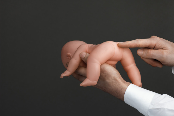 Männerhände mit einer Babypuppe - Foto, Bild