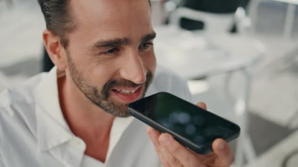 Closeup businessman send voice mail using cellphone in summer terrace. Happy employee talk using virtual assistant. Smiling man hold mobile phone listening message at cafe. Digital lifestyle concept  - Footage, Video