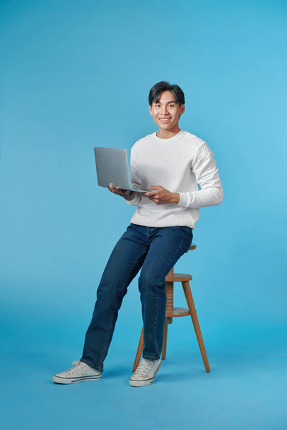 Πλήρες μήκος των ελκυστικών άνθρωπος υπάλληλος γραφείου κάθονται σκαμνί χρήση netbook συνέδριο σε μπλε φόντο - Φωτογραφία, εικόνα