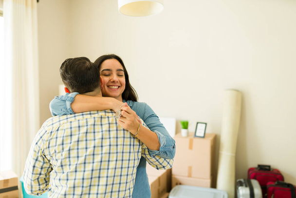 Atractiva esposa abrazando a su marido y celebrando conseguir un nuevo crédito hipotecario para mudarse a una nueva casa juntos - Foto, imagen