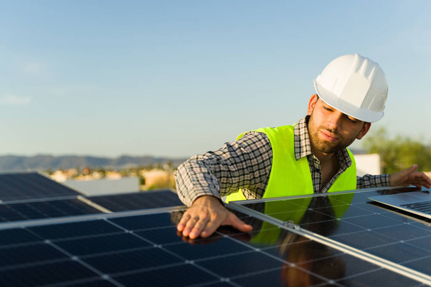 Jóképű mérnök ellenőrzi a napelemeket és a fotovoltaikus cellákat, miközben tiszta energiával dolgozik. - Fotó, kép