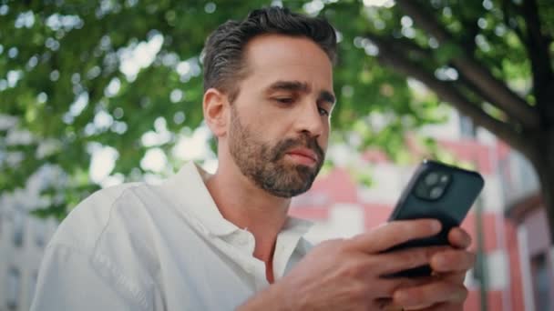 Homem de negócios hispânico enviando mensagens de telefone celular no terraço do café de perto. Homem barbudo focado segurando celular digitando e-mail no centro da cidade. Morena gerente trabalhando no local de trabalho ar fresco - Filmagem, Vídeo