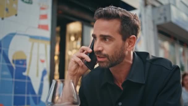 Irritated business man calling cellphone at street bar closeup. Furious angry guy speaking mobile phone emotionally at cafe. Mad macho quarrelling with girlfriend at smartphone call alone outdoors - Footage, Video