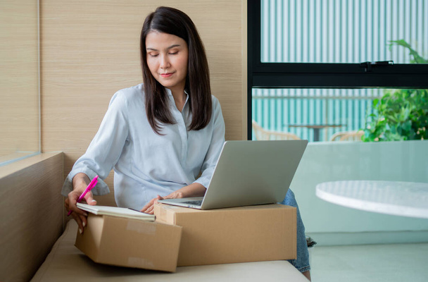 Happy young Asian woman entrepreneur, Smile for sales success after checking order from online shopping store in a laptop at home office, Concept of merchant business online and eCommerce - Photo, Image
