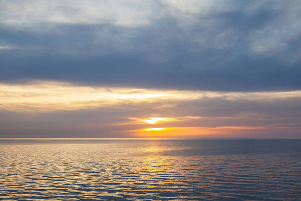 Západ slunce a moře. Večerní krajina modré oblačné oblohy s jasně žlutým slunečním světlem  - Fotografie, Obrázek