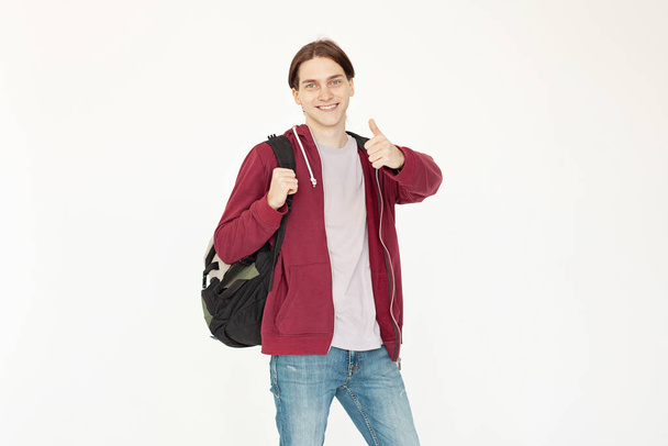 Fiatal férfi diák mutatja hüvelykujj fel álló fehér háttér - Fotó, kép