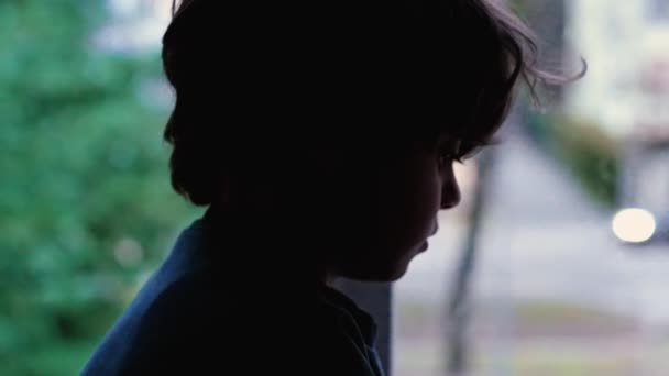 Melancholisch depressives Kind, das am Fenster eines Mehrfamilienhauses sitzt und in stiller Verzweiflung sitzt. Trauriges Kind mit Depressionen und Traurigkeit - Filmmaterial, Video