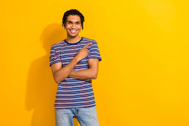 Portrait of toothy beaming man with piercing wear stylish t-shirt indicating at discount empty space isolated on yellow color background. - Zdjęcie, obraz