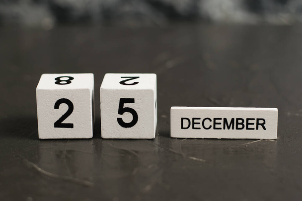 Calendrier en bois avec la date du 25 décembre sur un fond texturé foncé avec espace de copie. - Photo, image
