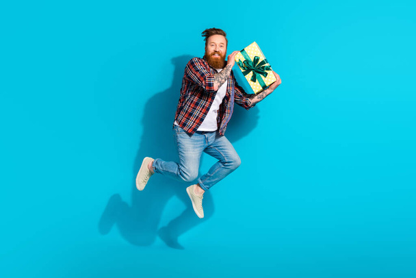 Full body length photo of friendly energetic guy congratulates holding wrapped new giftbox happy birthday isolated on blue color background. - Foto, imagen