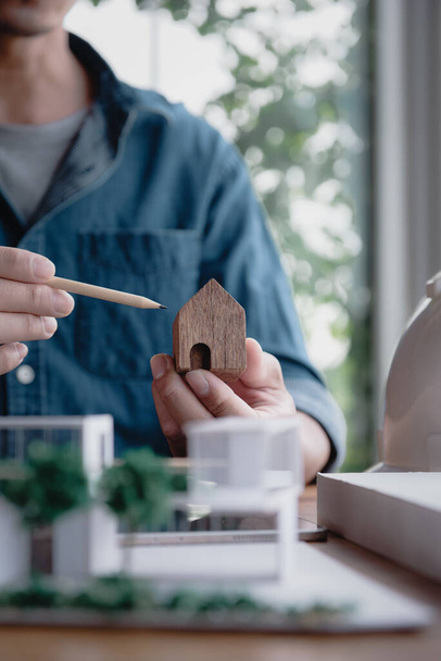 Architectuur professional werken in het home design concept, gebruik een potlood wijzen naar een houten huisje symbool met de moderne home model op de werkplek op kantoor. Verticaal beeld. - Foto, afbeelding