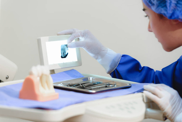 Donna dentista in possesso e in cerca di mordere ala immagine a raggi X in studio dentista. Concentrarsi sull'immagine a raggi X. - Foto, immagini